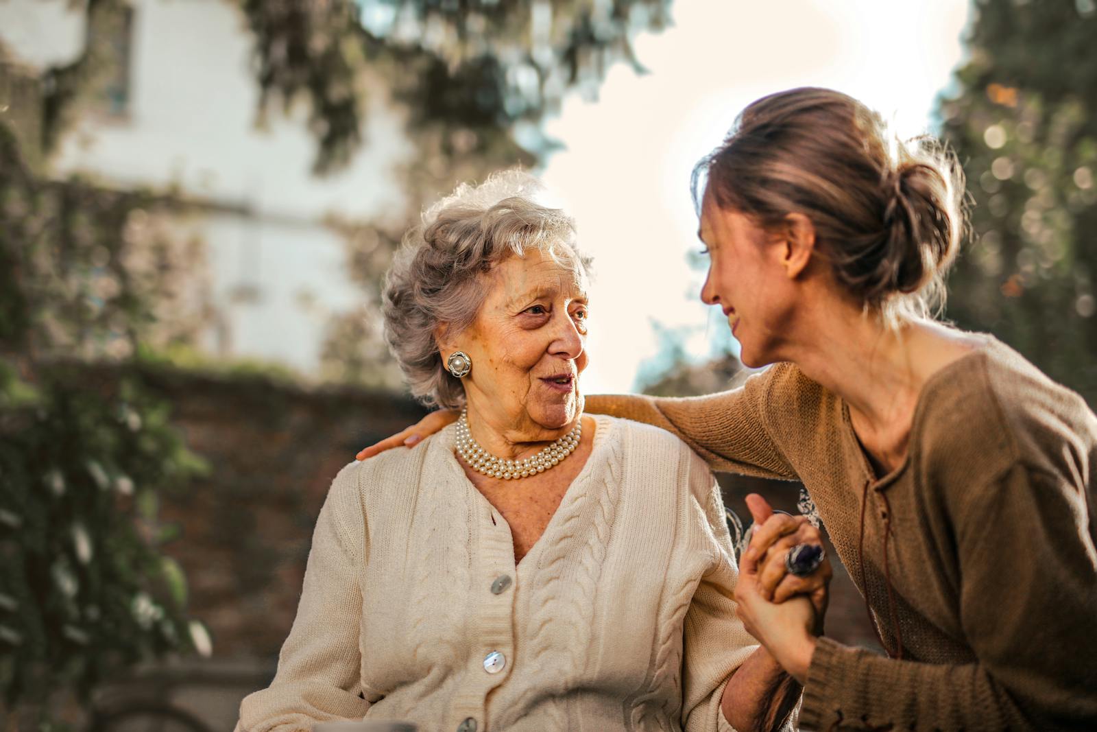 A senior woman laughing with her companion in a sunlit garden