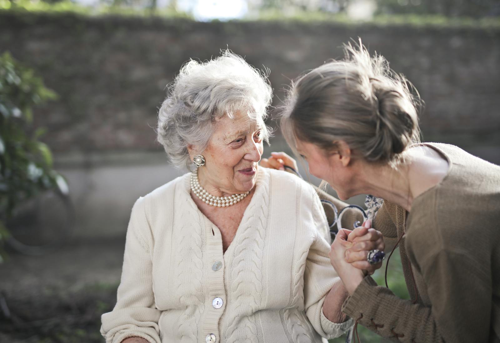 A senior woman and her companion holding hands in a garden
